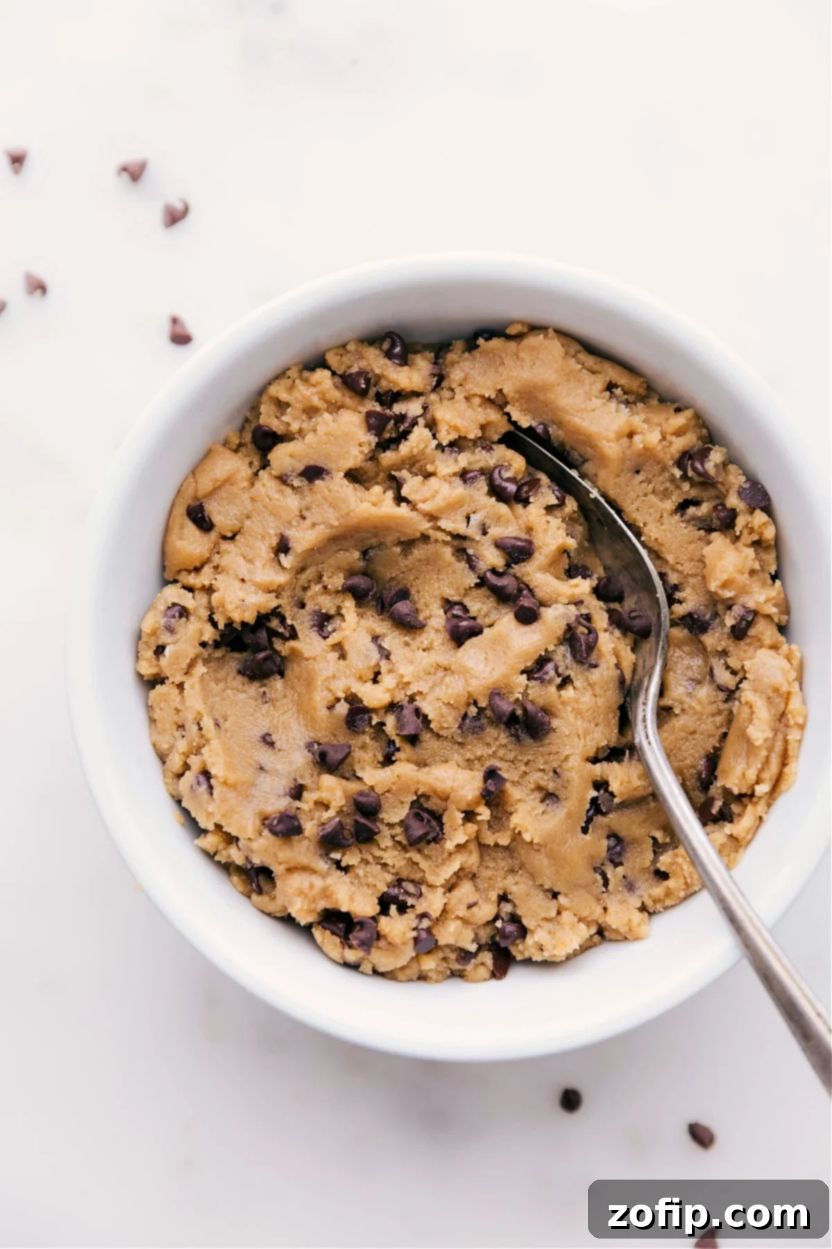 A bowl of rich, chocolate chip edible cookie dough, perfectly scooped and ready to be devoured, highlighting its tempting texture.