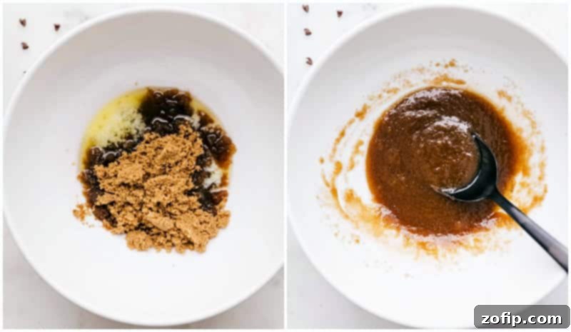 A close-up shot of a whisk vigorously mixing together rich, melted butter with both brown and white sugars in a clear glass bowl, creating a smooth, creamy base for the edible cookie dough, emphasizing the initial step of combining wet ingredients.