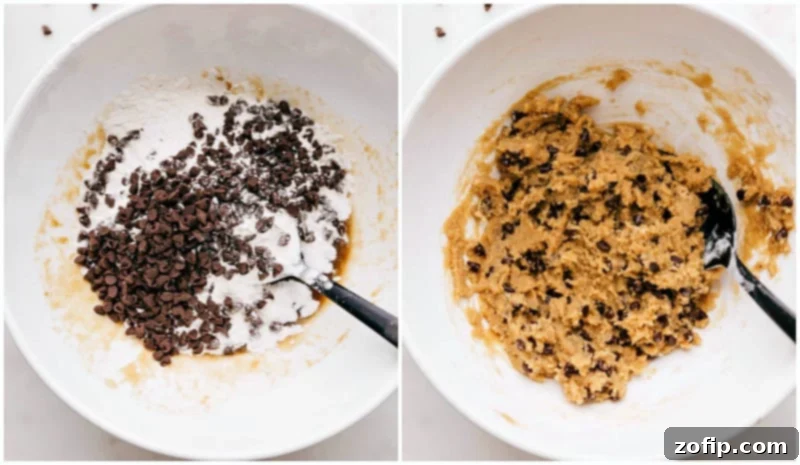 A person's hands are actively mixing heat-treated flour and mini chocolate chips into a bowl with a creamy butter and sugar base, illustrating the final stages of preparing the edible cookie dough.
