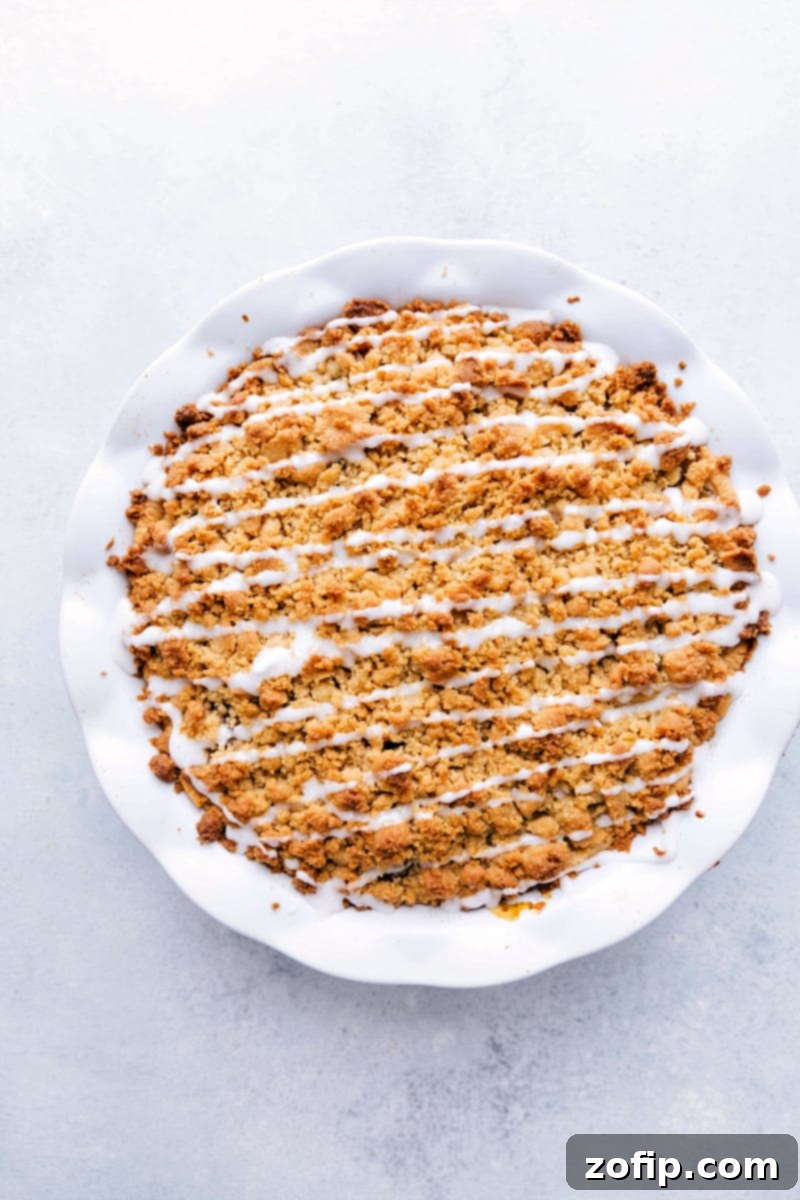 Overhead image of a beautifully baked Cinnamon Roll Apple Pie, showcasing its golden crumble topping and a unique swirled crust, ready to be served.