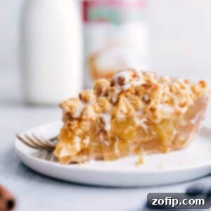 A delicious Cinnamon Roll Apple Pie, freshly baked and elegantly drizzled with sweet icing, ready to be served.