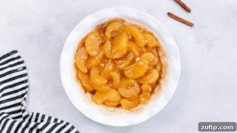 Process image showing apple pie filling being spooned generously into the unique cinnamon roll crust.