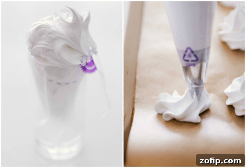 Meringue cookie batter being piped from a pastry bag onto a parchment-lined baking sheet, showing precision and readiness for baking.
