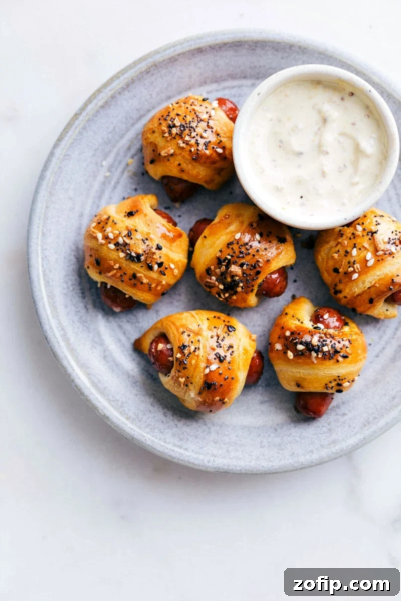 Perfectly baked Pigs in a Blanket with everything bagel seasoning on a serving platter.