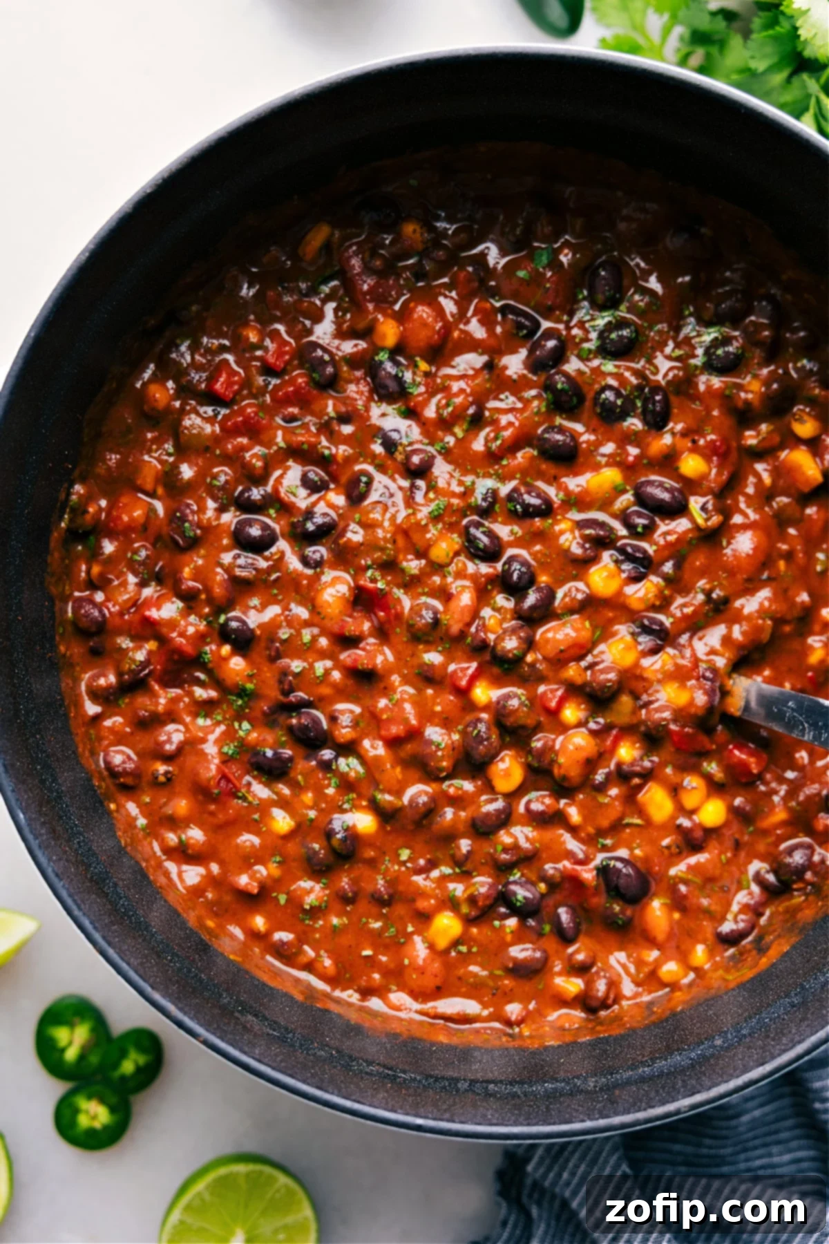 A steaming pot of rich and hearty vegetarian chili, garnished with fresh cilantro, ready to be served and enjoyed.