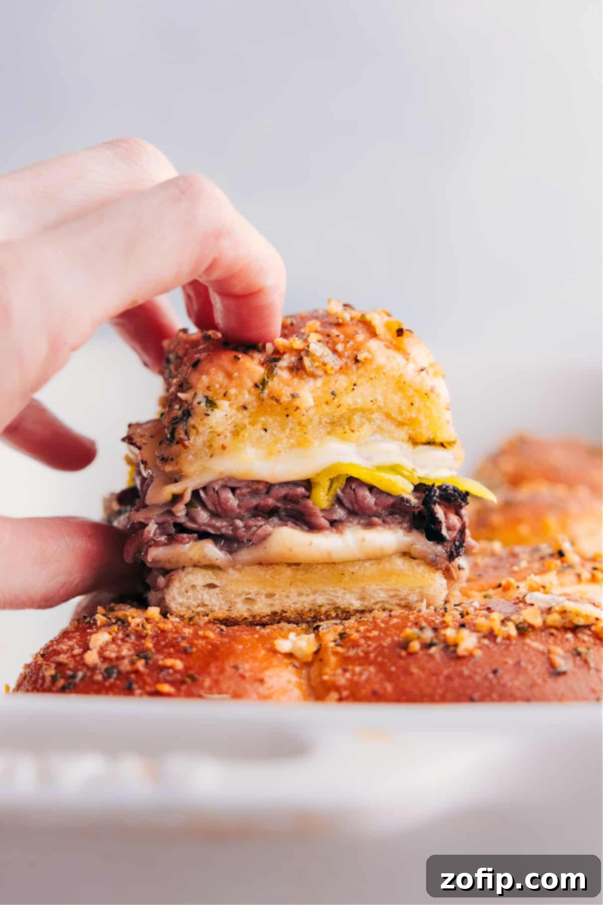 Freshly baked Italian Beef Sliders, golden brown and cheesy, arranged on a serving platter.