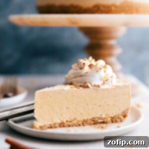 Effortless Autumn Pumpkin Cheesecake 4 A tempting slice of no-bake pumpkin cheesecake with the whole cheesecake in the background, ready to be savored.