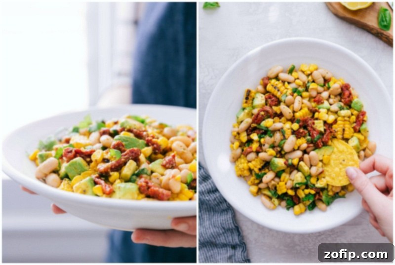 This White Bean Salsa with creamy avocado, crisp corn, savory sun-dried tomatoes, fresh lemon, and sweet basil is our latest obsession! It's perfect over grilled Pesto Chicken! Recipe via Chelseasmessyapron #healthy #keto #whole #protein #whole30 #best #avocado #corn #sundriedtomatoes #clean #cleaneating #whitebean #salsa A chip being dipped into a bowl of White Bean Salsa, ready to be enjoyed