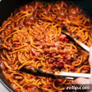 Taco Spaghetti in a pot with tongs about to scoop some up.