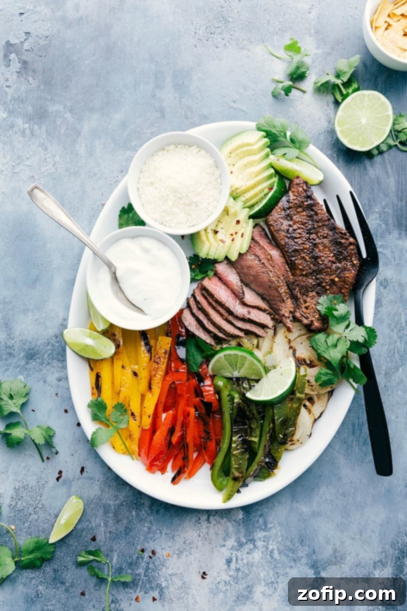 Plate of steak fajitas with bell peppers and onions, garnished with cilantro and lime.