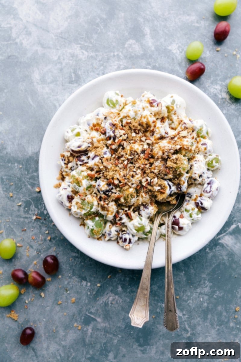 Ready-to-eat Grape Salad with a generous layer of brown sugar and pecans on top, served in a decorative bowl.