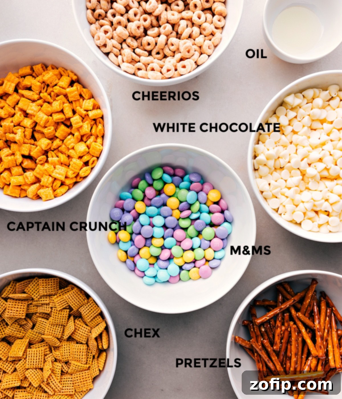 All the ingredients prepped and ready for easy assembly—Cheerios, oil, white chocolate, Cap’n Crunch, M&Ms, pretzels, and Chex cereal.