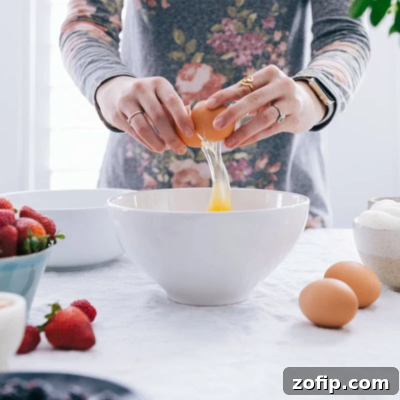 An egg being cracked into a mixing bowl, symbolizing the start of a delicious waffle recipe.