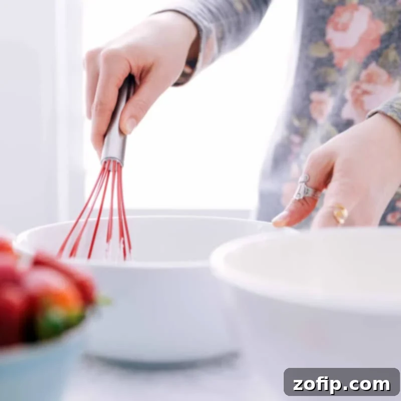 Wet ingredients being thoroughly whisked together in a bowl, a crucial step for the best Waffle Recipe.