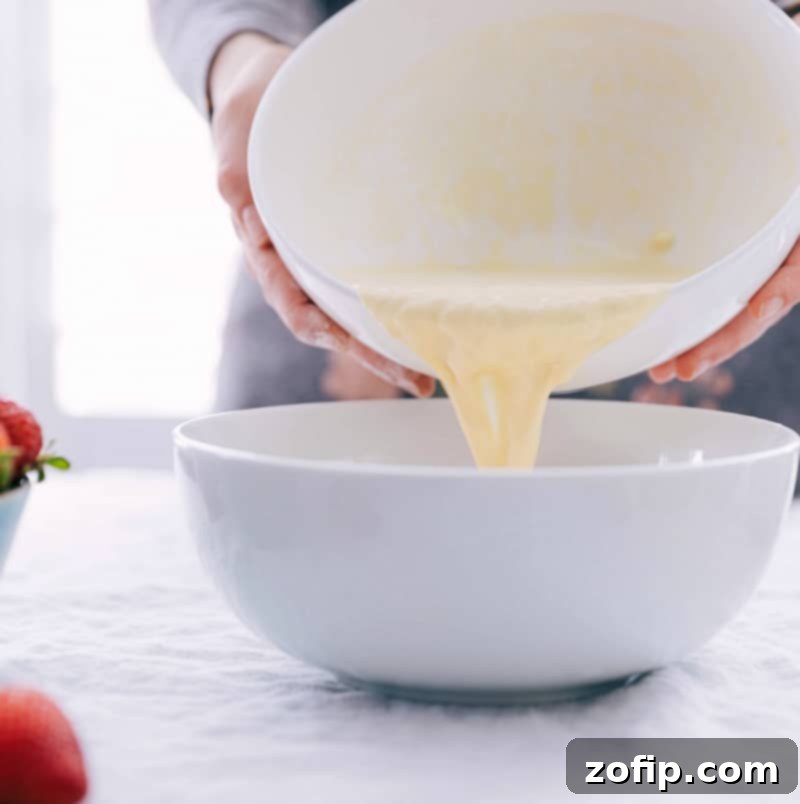 Wet ingredients being carefully poured into the well of dry ingredients for this Waffle Recipe, ensuring proper mixing.