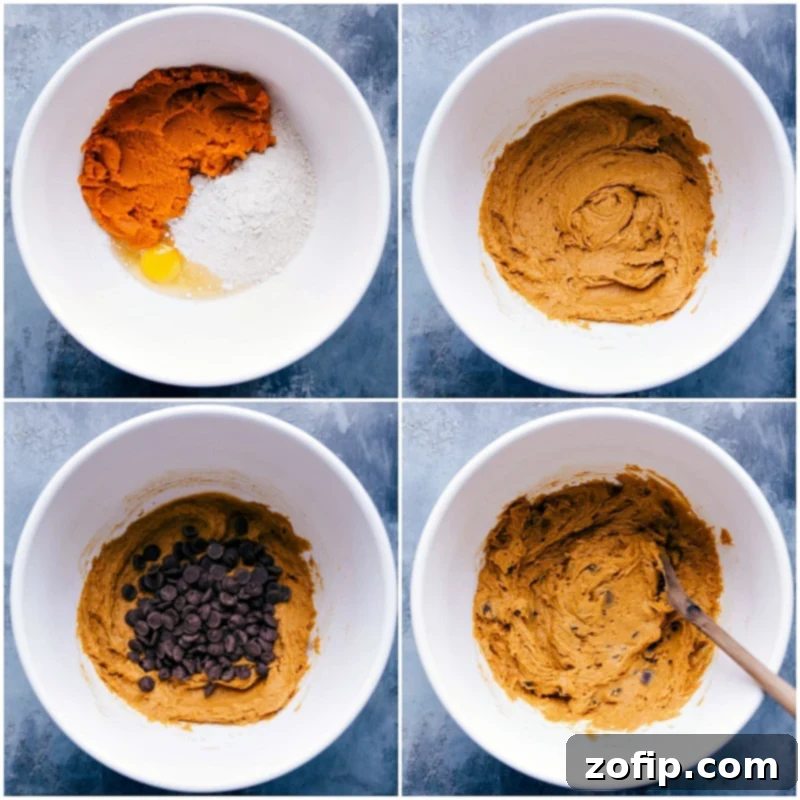 A close-up shot of a thick, golden-orange pumpkin cookie dough being mixed in a large bowl, showcasing its rich texture and readiness for baking.