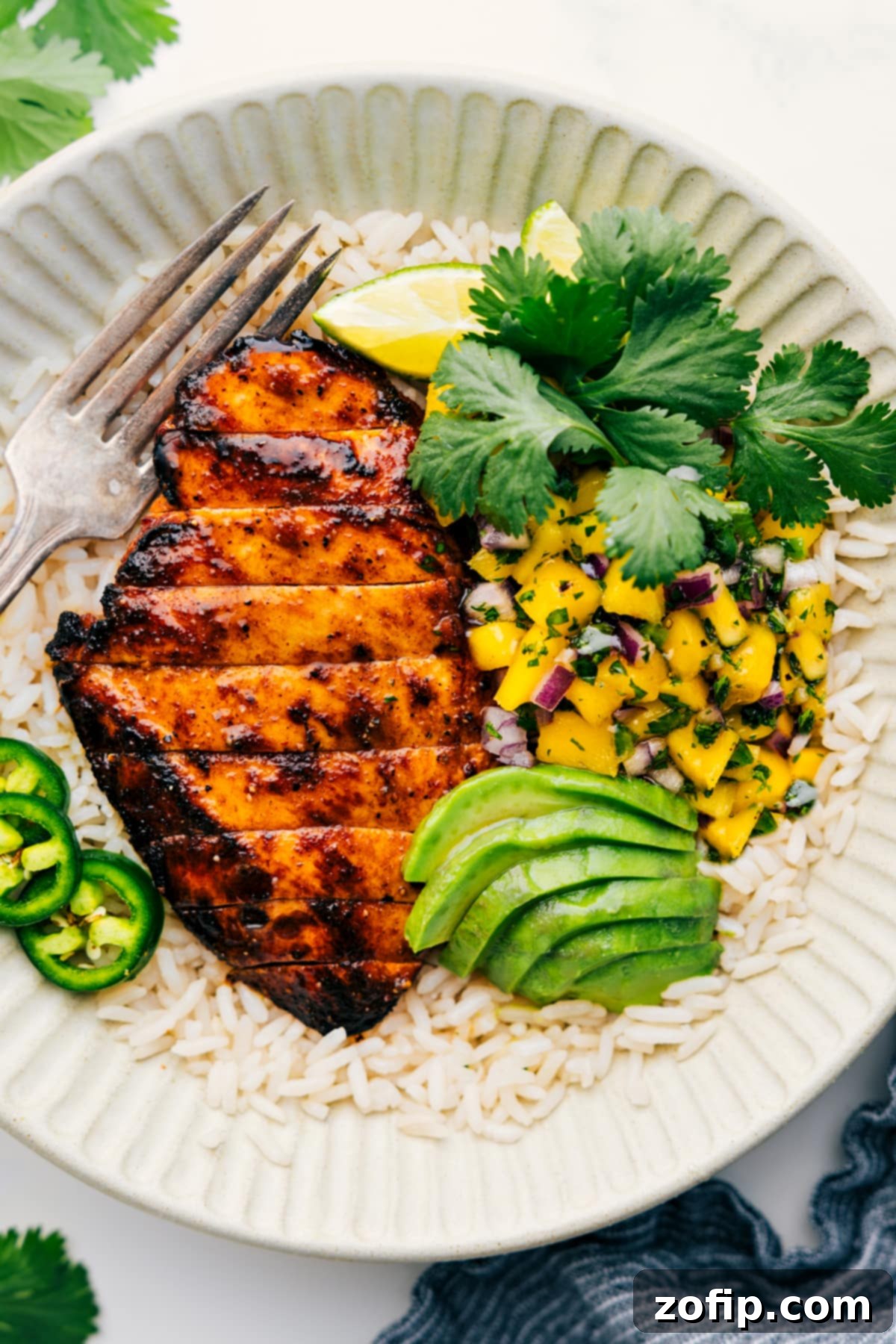 The Perfect Summer Dinner: Mango Chicken with Fresh Salsa Grilled Mango Chicken on a bed of fluffy white rice, adorned with a vibrant mango salsa and sprinkled with fresh cilantro, ready to be served.