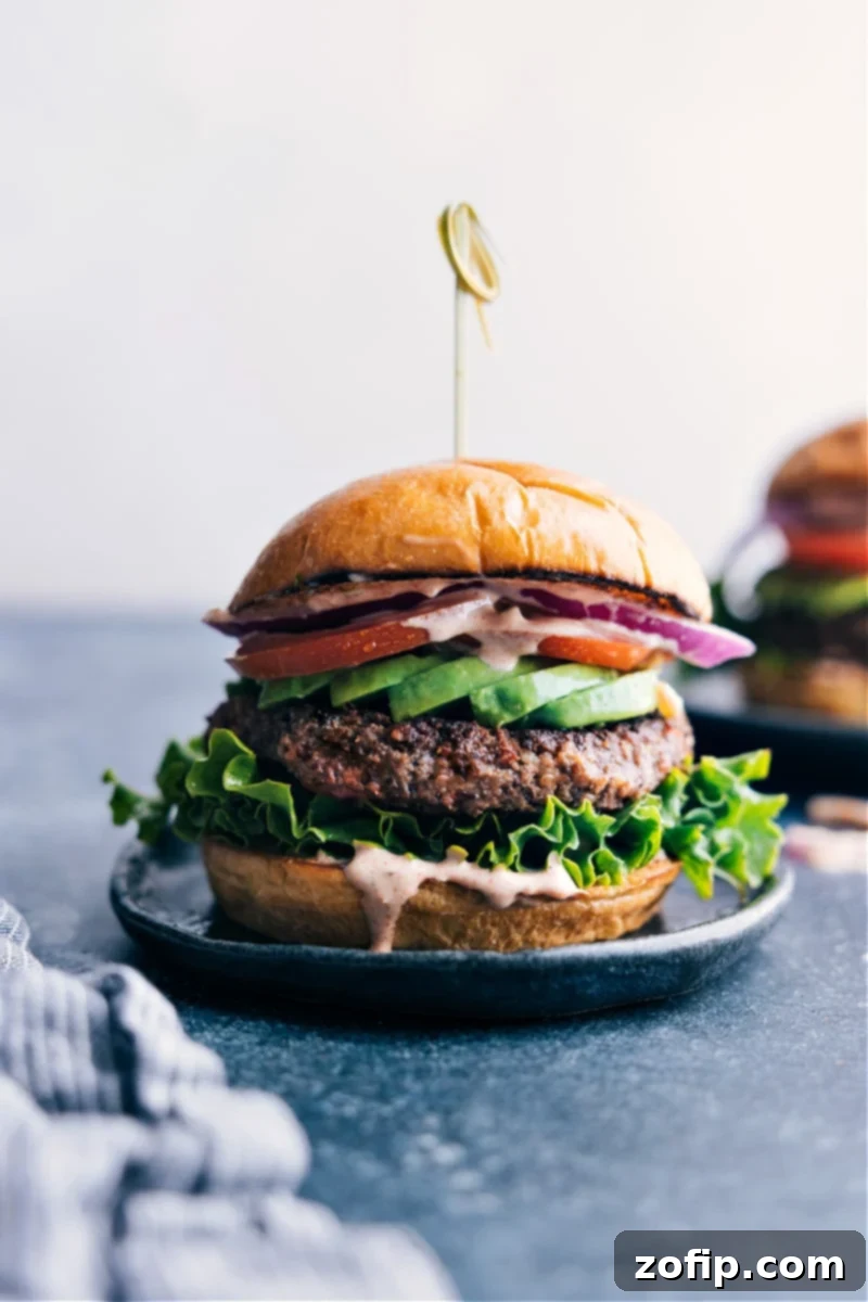 Black Bean Burger with Fresh Vegetables and Sauce A perfectly cooked black bean burger, richly topped with vibrant fresh vegetables and a savory sauce, served on a plate.