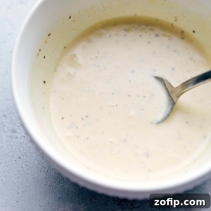 Dressing ingredients being mixed together in a small bowl, combining flavors for a smooth and flavorful sauce, essential for a perfect pineapple chicken salad.