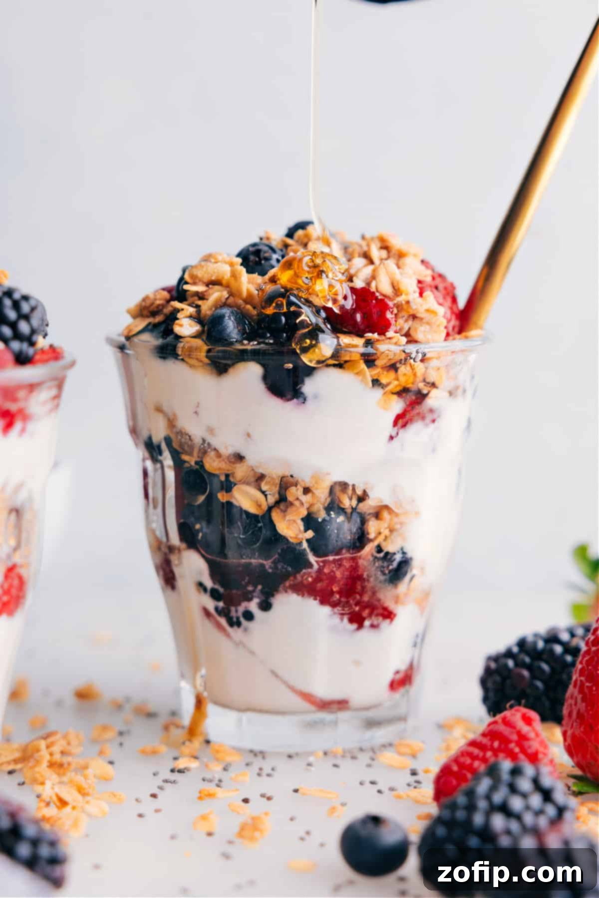 Drizzling Honey on Yogurt Parfait A hand drizzling golden honey over the top of a beautifully layered yogurt parfait, enhancing its natural sweetness and adding a glossy finish.