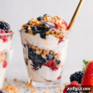 Layered Yogurt Parfait Perfection 3 Layered yogurt parfait in a cup, showcasing layers of creamy yogurt, fresh fruit, drizzles of honey, and crunchy granola on top.