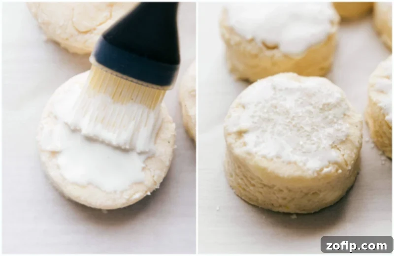 Heavy cream and coarse sugar being brushed and sprinkled on the tops of the biscuits before baking, enhancing their golden color and texture.