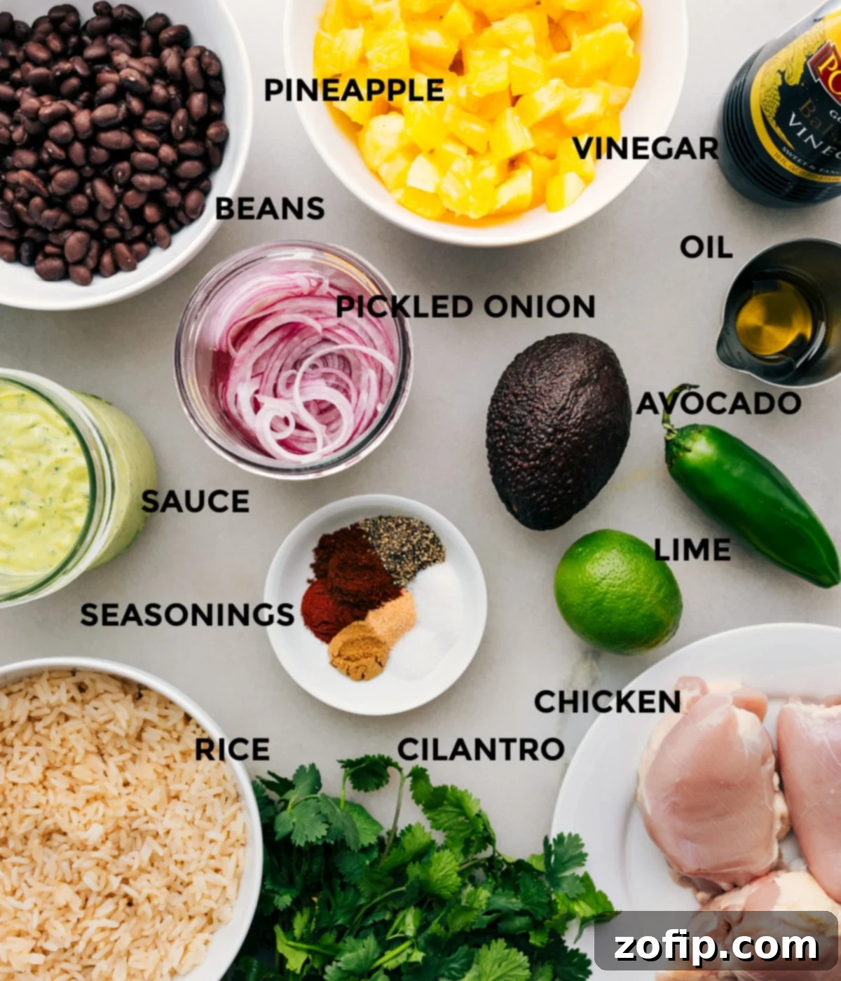Essential Ingredients for a Flavorful Chicken Rice Bowl A vibrant display of all fresh ingredients prepped for the Chicken Rice Bowl recipe, including chicken thighs, spices, avocado, oranges, cilantro, and more.