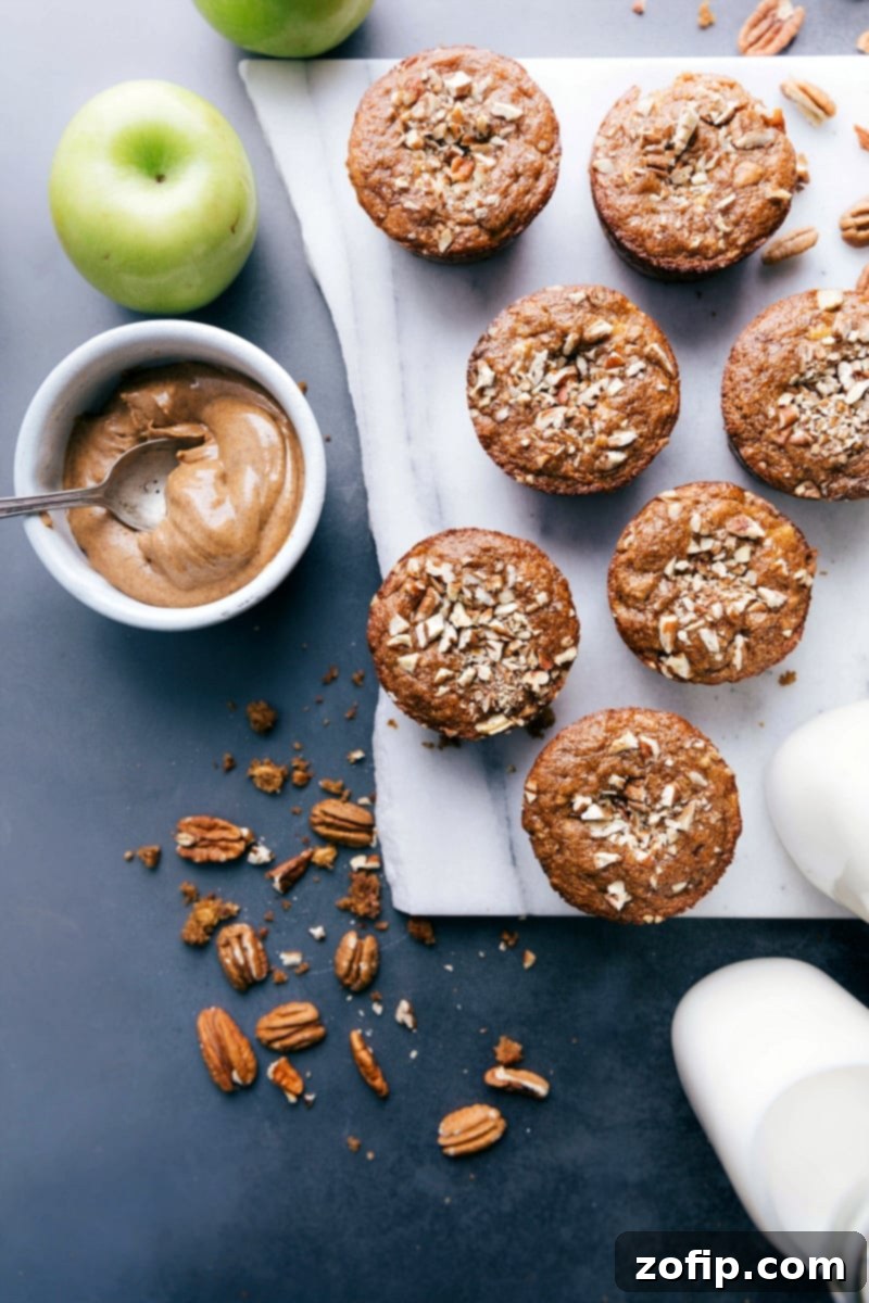 Freshly baked gluten-free apple muffins, golden brown and perfectly domed, cooling on a rack, garnished with a sprinkle of extra pecans.