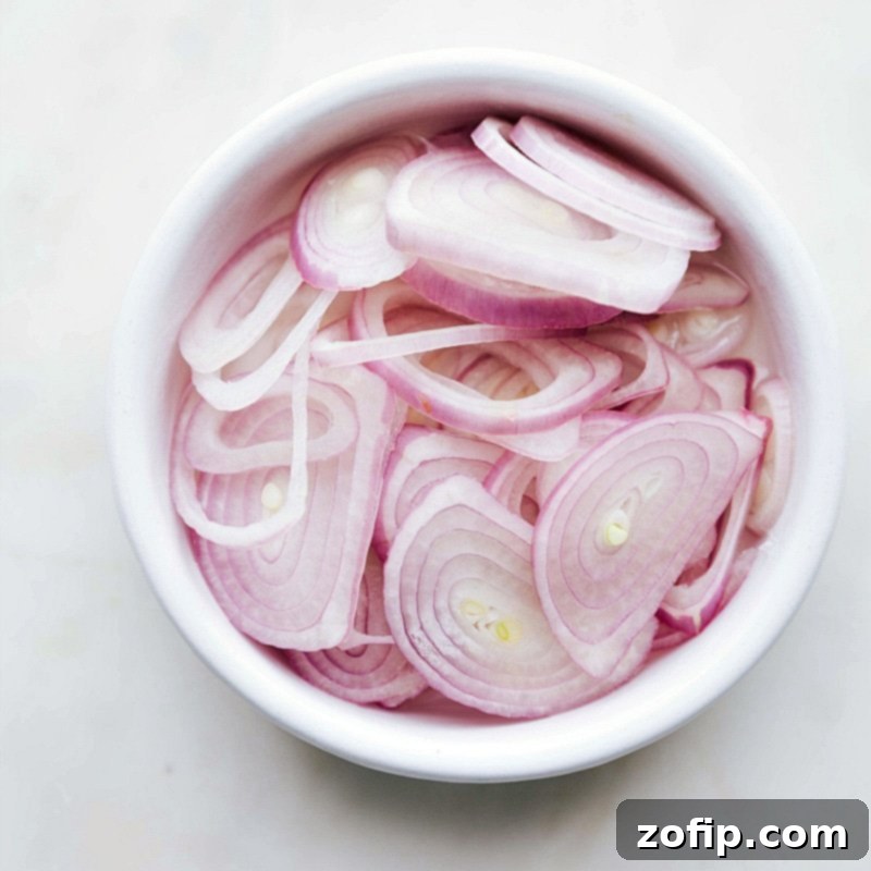 Fresh shallots finely sliced, ready to be used as a topping for the dish.