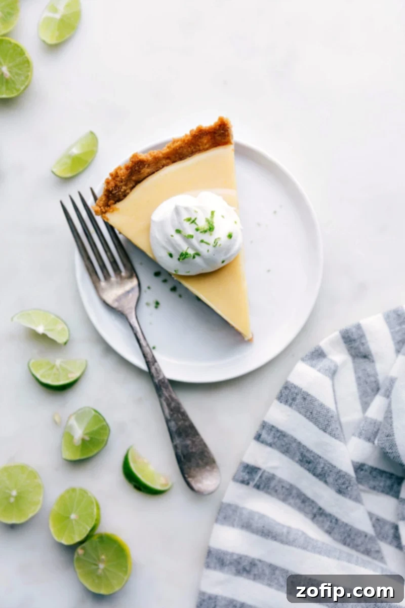 Slice of creamy key lime pie with a dollop of whipped cream on top, garnished with lime zest.