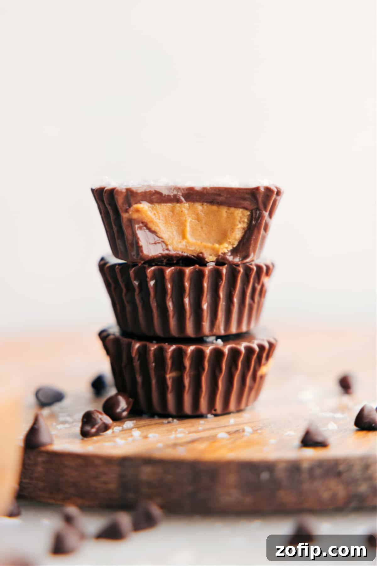 Stacked homemade peanut butter cups with one having a bite taken out, revealing the creamy peanut butter filling and chocolate layers.