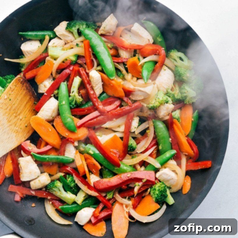 Mixing fresh vegetables and meat in the skillet.