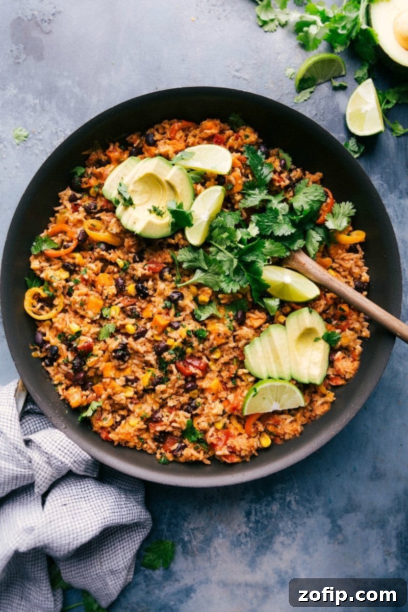 One-skillet sweet potato burrito bowl loaded with toppings, served directly in the skillet, showcasing vibrant ingredients.