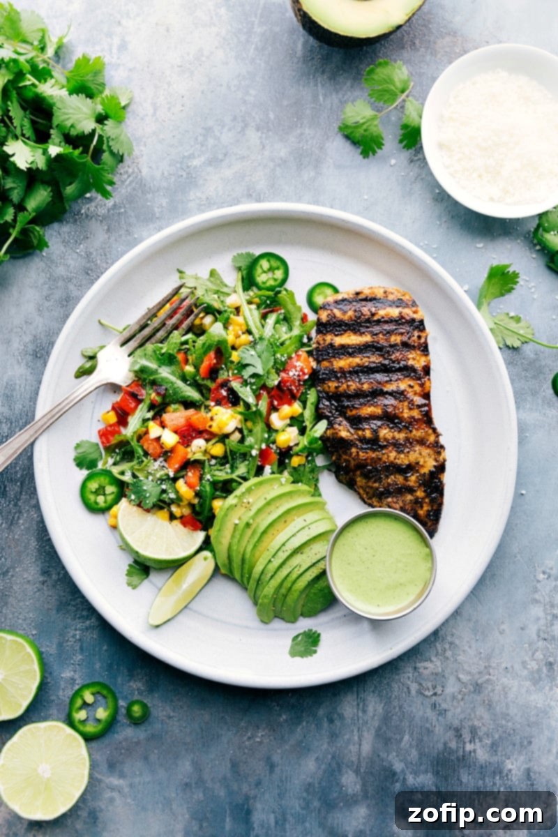 A plate filled with perfectly grilled Peruvian chicken, a fresh, vibrant arugula-corn salad, creamy avocado slices, and a rich, zesty green sauce, showcasing a healthy and delicious meal ready to be enjoyed.