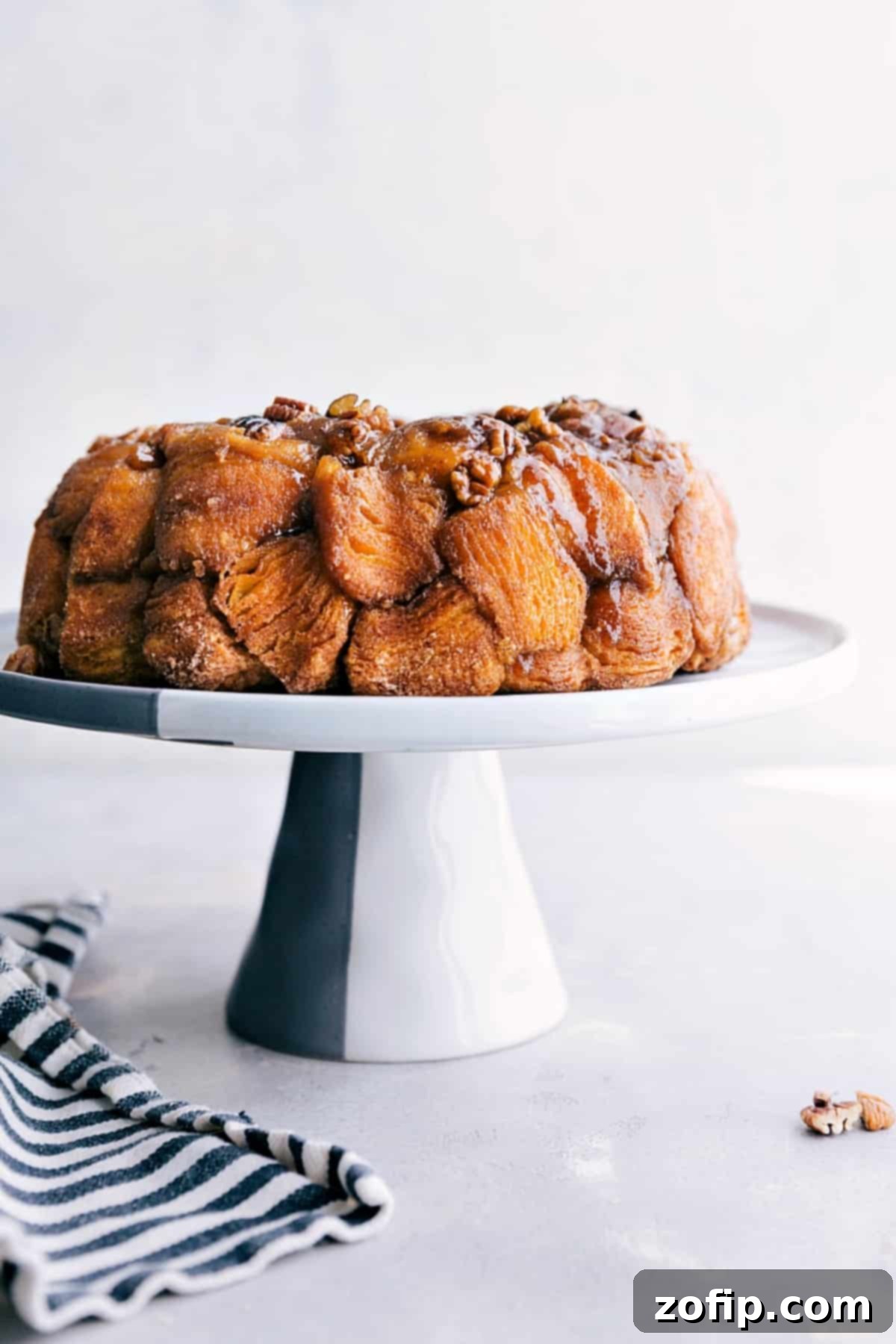 Finished Monkey Bread on Cake Stand Freshly baked Monkey Bread, golden brown and glistening with caramel, presented on an elegant cake stand, ready to be pulled apart and enjoyed.