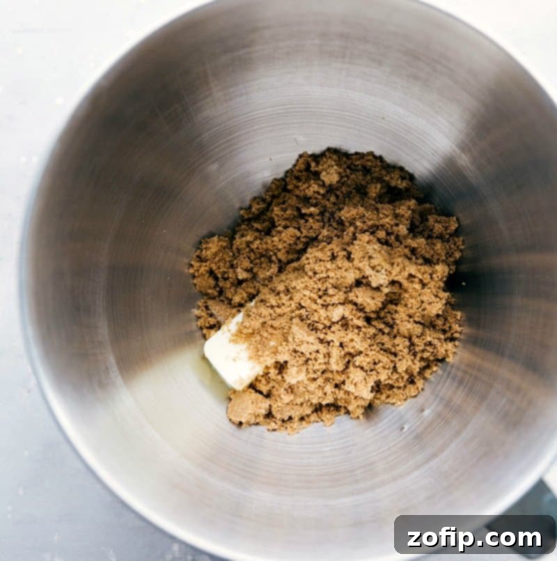 Close-up of butter and dark brown sugar being creamed together in a mixing bowl, showing the rich, golden texture.