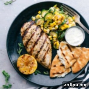 A plate featuring Greek chicken served with naan bread and a zucchini and corn salad, offering a delicious and flavor-packed meal.