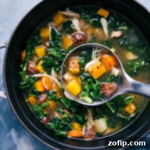 A close-up of a rustic pot filled with steaming chicken vegetable soup, featuring tender shredded chicken, colorful roasted vegetables, and vibrant kale, ready to be served.