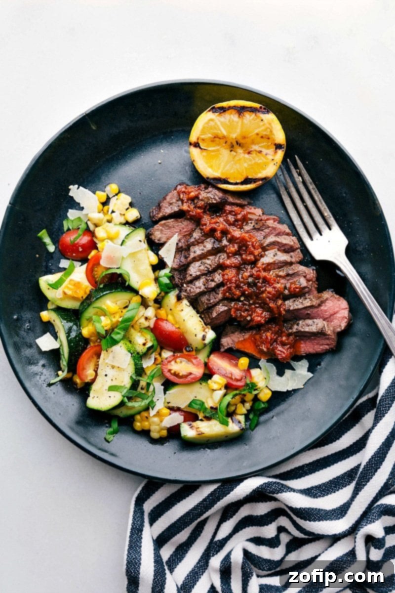 A succulent and tender grilled flat iron steak served with a refreshing zucchini and corn salad on the side, promising a delicious and satisfying meal.