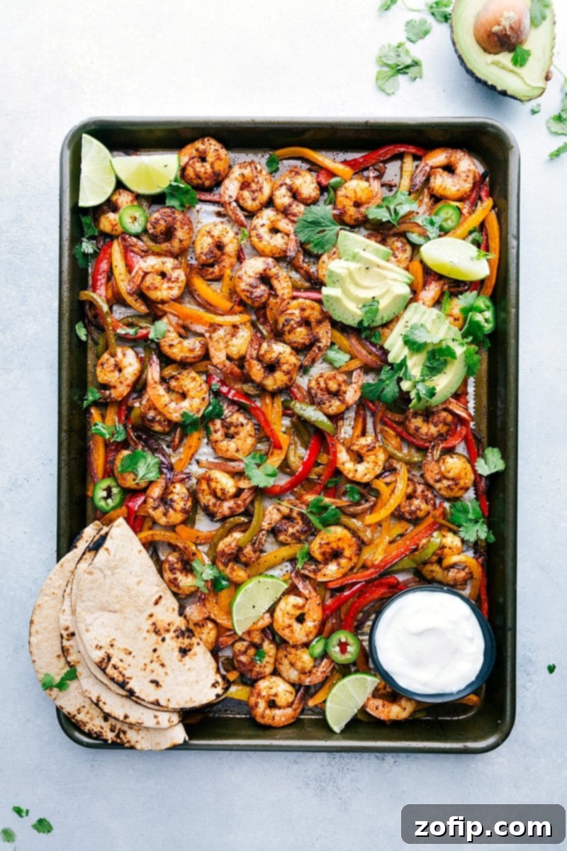 Freshly baked shrimp fajitas on a sheet pan, accompanied by tortillas and a variety of toppings, all set for assembly into a mouthwatering and savory meal.