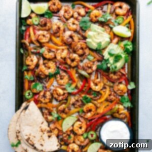 Freshly baked shrimp fajitas on a sheet pan, accompanied by tortillas and a variety of toppings, all set for assembly into a mouthwatering and savory meal.