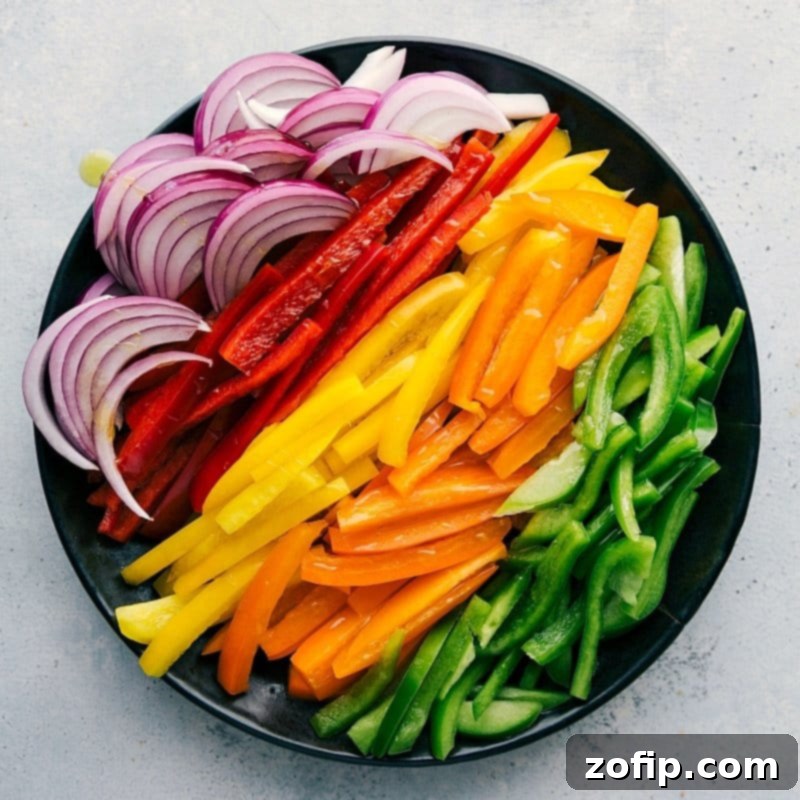 An assortment of sliced vegetables, including onions and various types of peppers, ready to be used in this recipe.