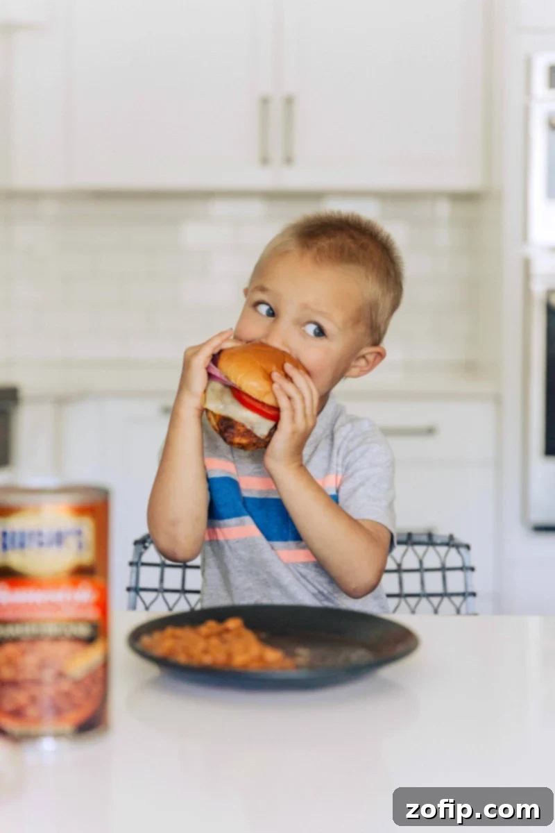 One of Chelsea's young sons is happily eating a completed chicken burger, demonstrating how much this meal is enjoyed by kids and adults alike.
