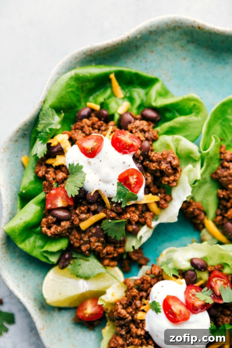 Completed Taco Lettuce Wraps - Topped with Sour Cream, Cheese, Tomatoes, and More Finished taco lettuce wraps topped with sour cream, cheese, cherry tomatoes, and other toppings, ready for a delightful meal.