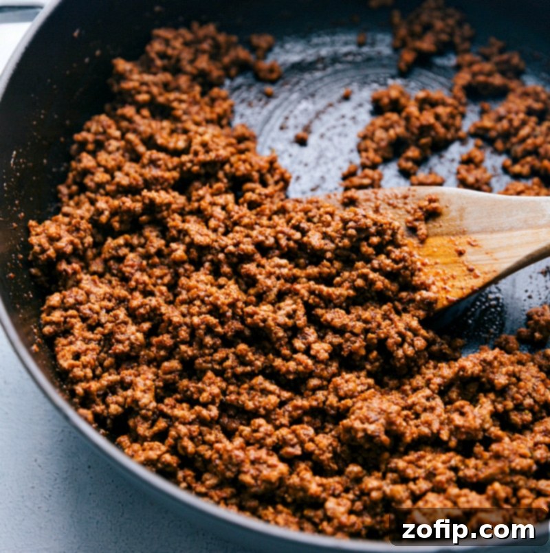 Cooking Ground Beef with Seasoning Blend - Infusing Flavors for Perfect Taste Ground beef cooking in a pan with a rich seasoning blend, absorbing all the delicious flavors until perfectly browned and ready for tacos.