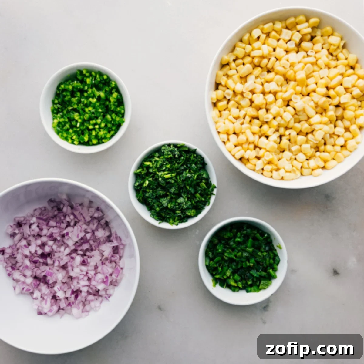 Red onion, cilantro, jalapeño, poblano, and corn prepped out on table Red onion, cilantro, jalapeño, poblano, and corn prepped and ready on a cutting board
