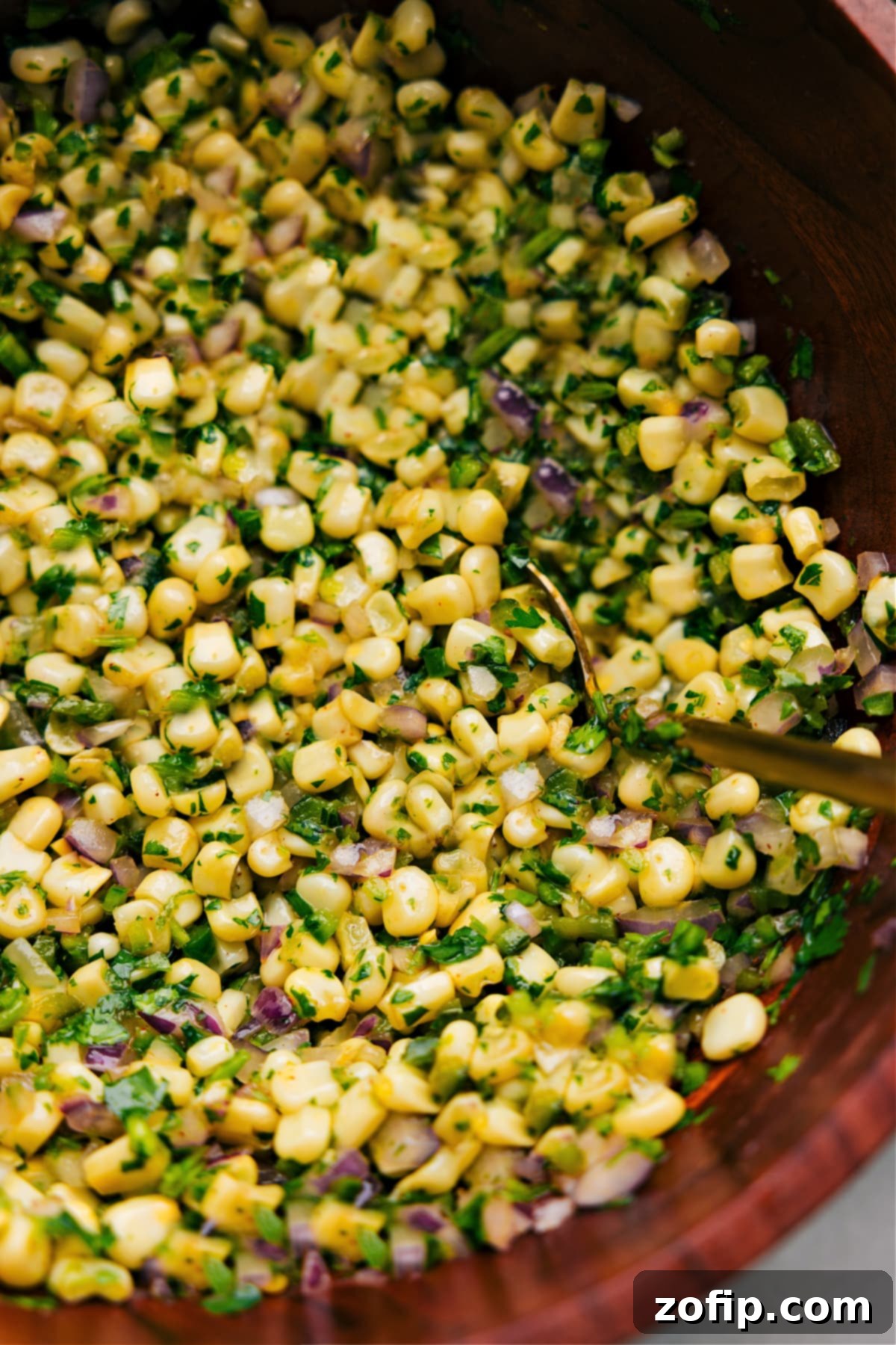 Up close photo of Chipotle Corn Salsa with spoon in it Up close photo of vibrant Chipotle Corn Salsa with a spoon ready for serving