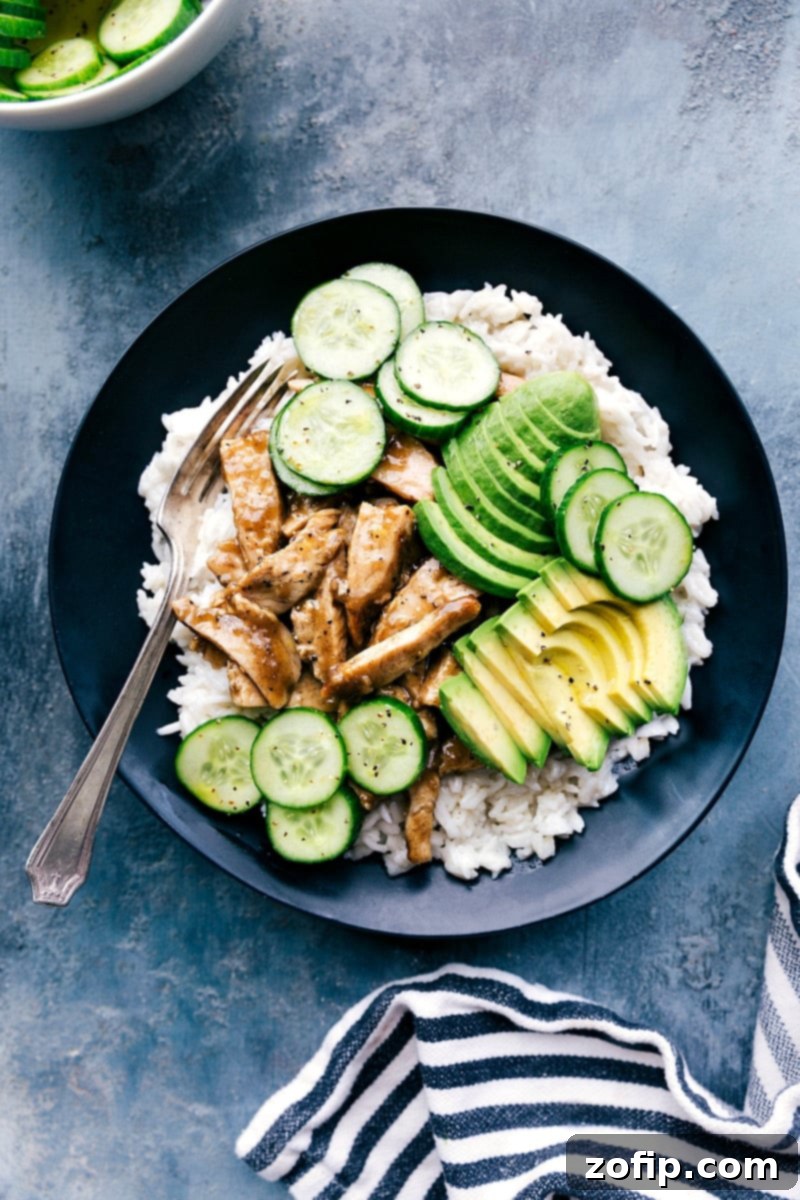 A delicious and balanced meal of apricot chicken in a bowl, elegantly presented with fluffy coconut rice, creamy avocado slices, and refreshing cucumber salad.