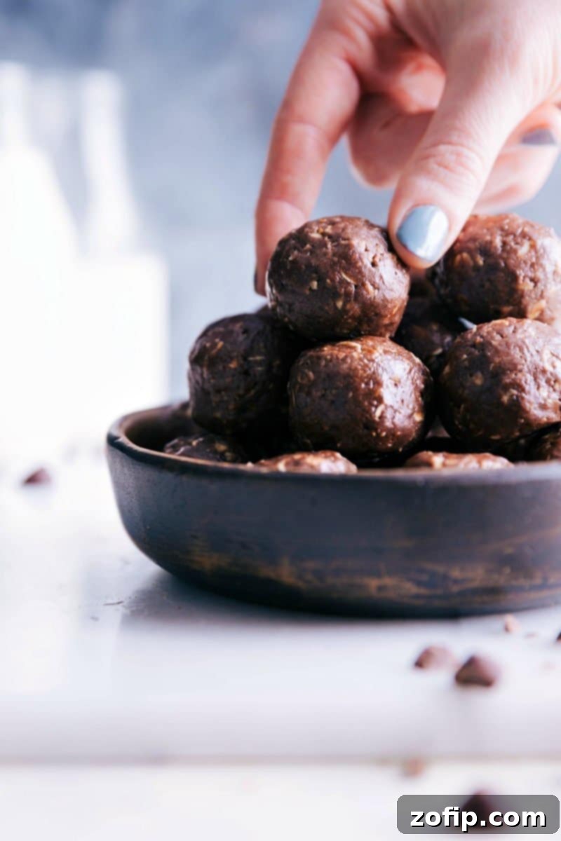 A beautifully arranged bowl filled with delectable chocolate energy bites, with a hand reaching in to pick one, highlighting their irresistible appeal and grab-and-go convenience.
