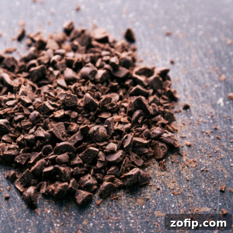 Finely chopped dark chocolate pieces arranged on a wooden cutting board, showcasing its rich texture and quality, ready for baking or snacking.
